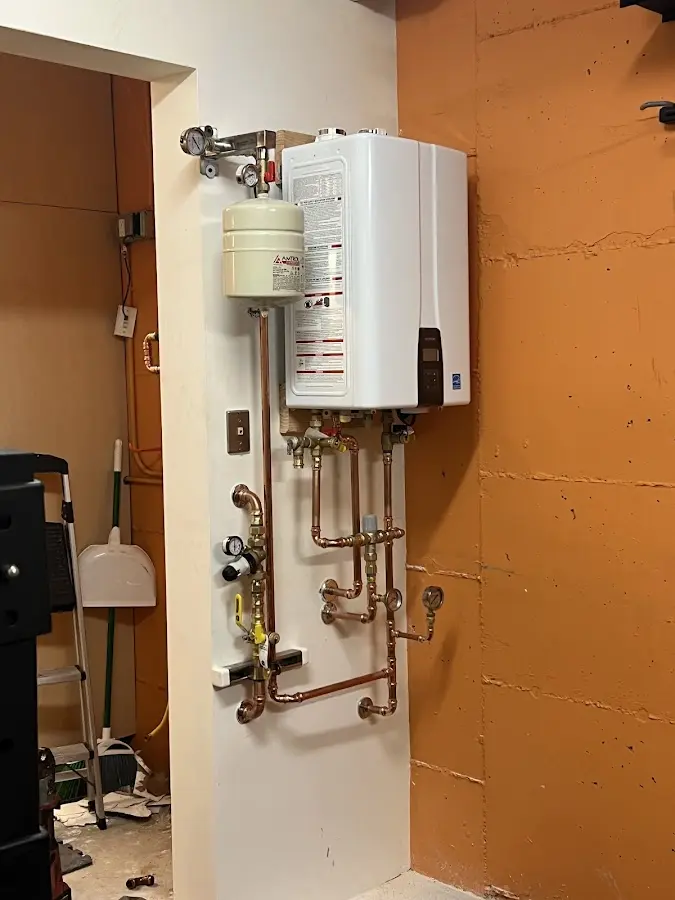 Plumbing technician inspecting water heater connections in Old Tappan